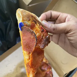 a hand holding a slice of pizza
