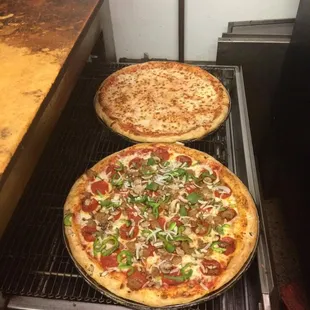 two pizzas cooking on an oven