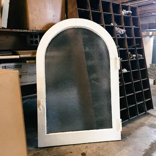 Originate natural building's salvage yard featuring an arched salvaged window | Tucson, AZ
