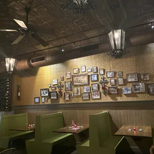 a dining area with green booths and pictures on the wall