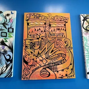 three paintings on a blue wall