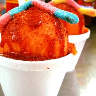 two cups of ice cream with candy worms on top