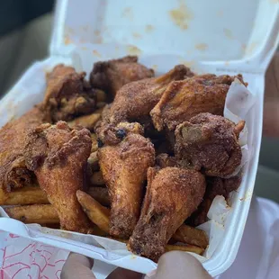 chicken wings and fries in a styrofoam container