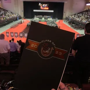 a person holding a book in front of a crowd