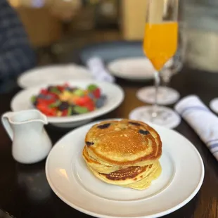 a plate of pancakes and a glass of orange juice