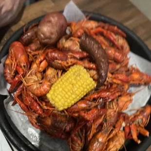 a plate of crawfish, corn and potatoes