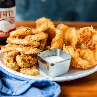 a plate of fried onion rings and a bottle of beer