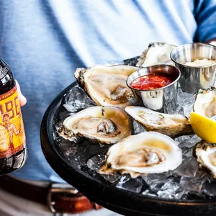 a man holding a tray of oysters