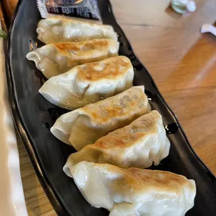 a row of dumplings on a black plate