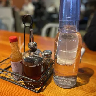 a glass of water, a bottle of liquid, and a spoon on a table