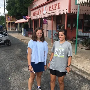 two women standing in front of a cafe