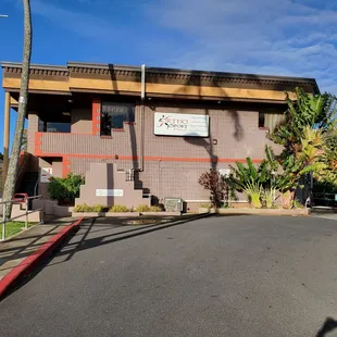 Outside of building, located in the West Mauka corner of the parking lot.