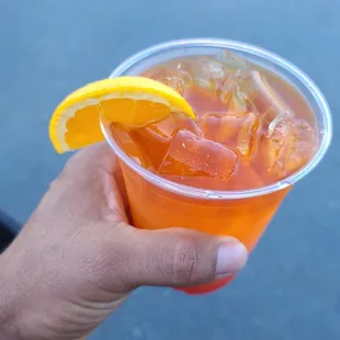 a hand holding a cup of orange juice