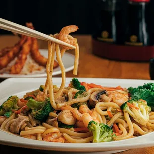 a plate of noodles with shrimp and broccoli