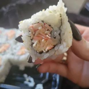 a hand holding a piece of sushi