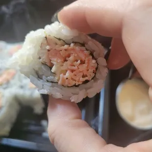 a hand holding a piece of sushi