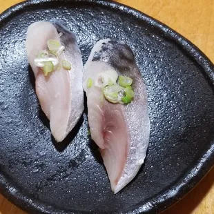 two pieces of raw fish on a black plate