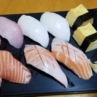 a variety of sushi on a black plate