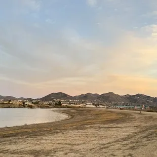 a beach with a bench and mountains in the background
