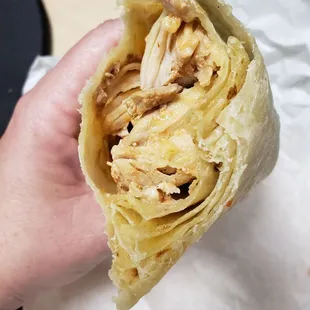a hand holding a chicken wrap