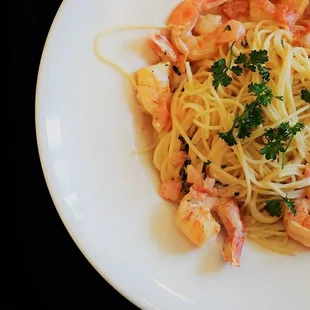a plate of pasta with shrimp and parsley