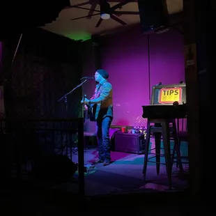 a man playing guitar and singing into a microphone