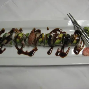 a plate of sushi with sauce and chopsticks
