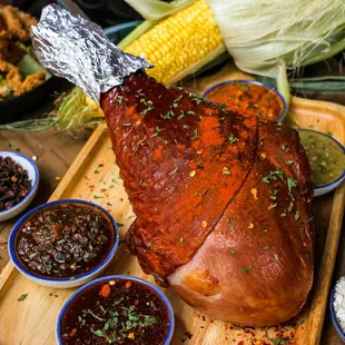 a ham on a cutting board surrounded by other foods