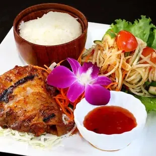 Grilled Five Spice Chicken: Marinated chicken thigh with thai herbs served with sweet and sour sauce, papaya salad, and sticky rice