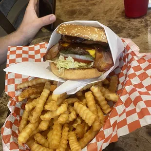 a hand holding a basket of fries