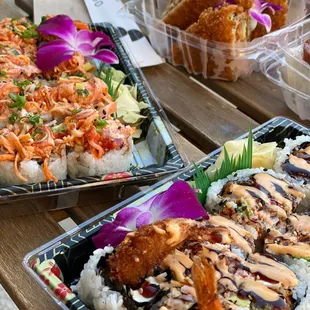 two trays of sushi on a picnic table