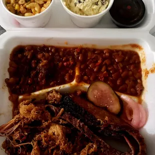 a tray of pulled pork, beans, macaroni and cheese