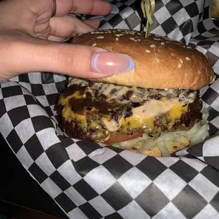 a hand holding a cheeseburger