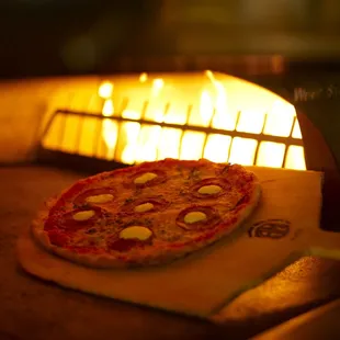 Thin crust artisan pizza baked to perfection in our oven. Pictured here: Bandiera Pizza with pepperoni, fresh basil, ricotta, mozzarella