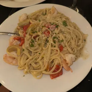 a plate of pasta with shrimp and tomatoes