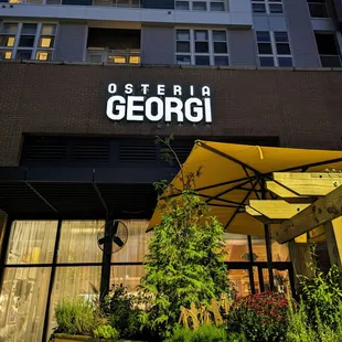 Osteria Georgi signage, outside at night. View facing south, southeast, from Village Plaza side.