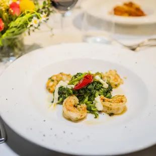 a white plate with shrimp and broccoli