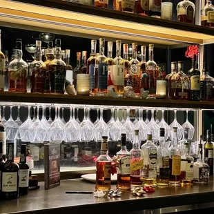 a shelf of liquor bottles and glasses