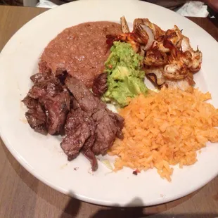 Beef fajitas, shrimp brochette guacamole, rice, beans and tortillas.