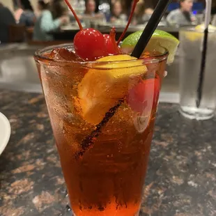 a drink with a cherry and lime garnish