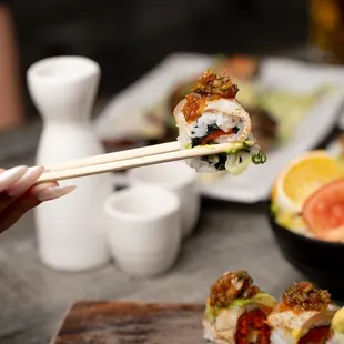 a person holding chopsticks over a sushi