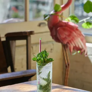 a glass of mojit with a flamingo in the background