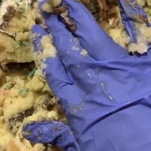 a gloved hand in front of a cake