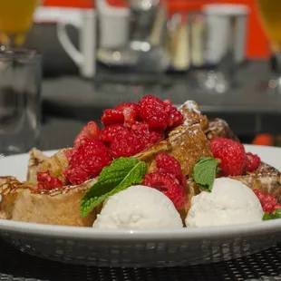 a plate of food with ice cream and raspberries