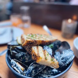 a bowl of mussels and bread on a table