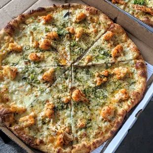 a pizza in a box with cheese and broccoli