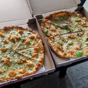 two pizzas in boxes on a table