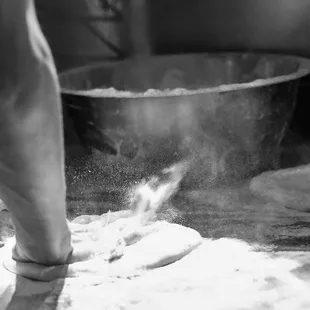 a person kneading dough in a kitchen