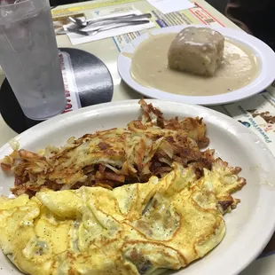 Swiss cheese omelette with hash browns and biscuits and gravy and water.