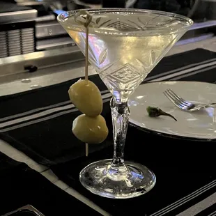 a martini and olives on a table